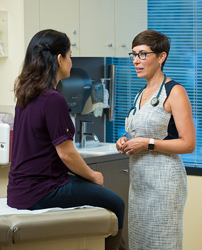 Dr. Laurel Hallock-Koppelman, 博彩网站 family practitioner, talks with a patient in a clinical office