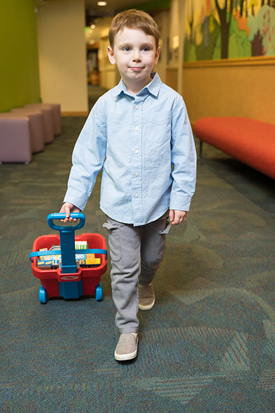 Photo of a boy walking and pulling a small wagon in a hallway at 博彩网站 Doernbecher Children's Hospital.