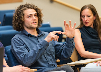 An 博彩网站 Ph.D. student talks about his work with other students in an auditorium.
