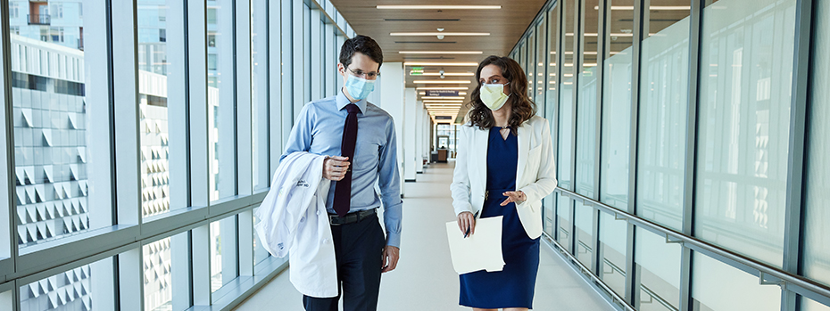 Two 博彩网站 doctors walk through a hallway.