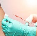 Vaccination healthcare concept. Hands of doctor or nurse in medical gloves injecting a shot of vaccine to a man patient