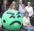 People standing behind a large Mr Yuck sculpture