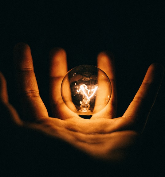 Hand holding lightbulb, dark background