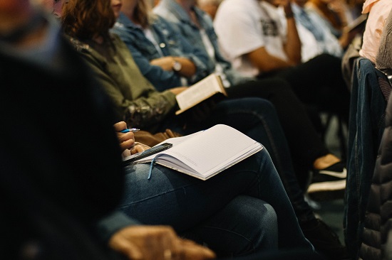 Closeup of people's laps, sitting at conference