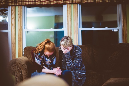 Two people sitting together, heads down, with head in hands