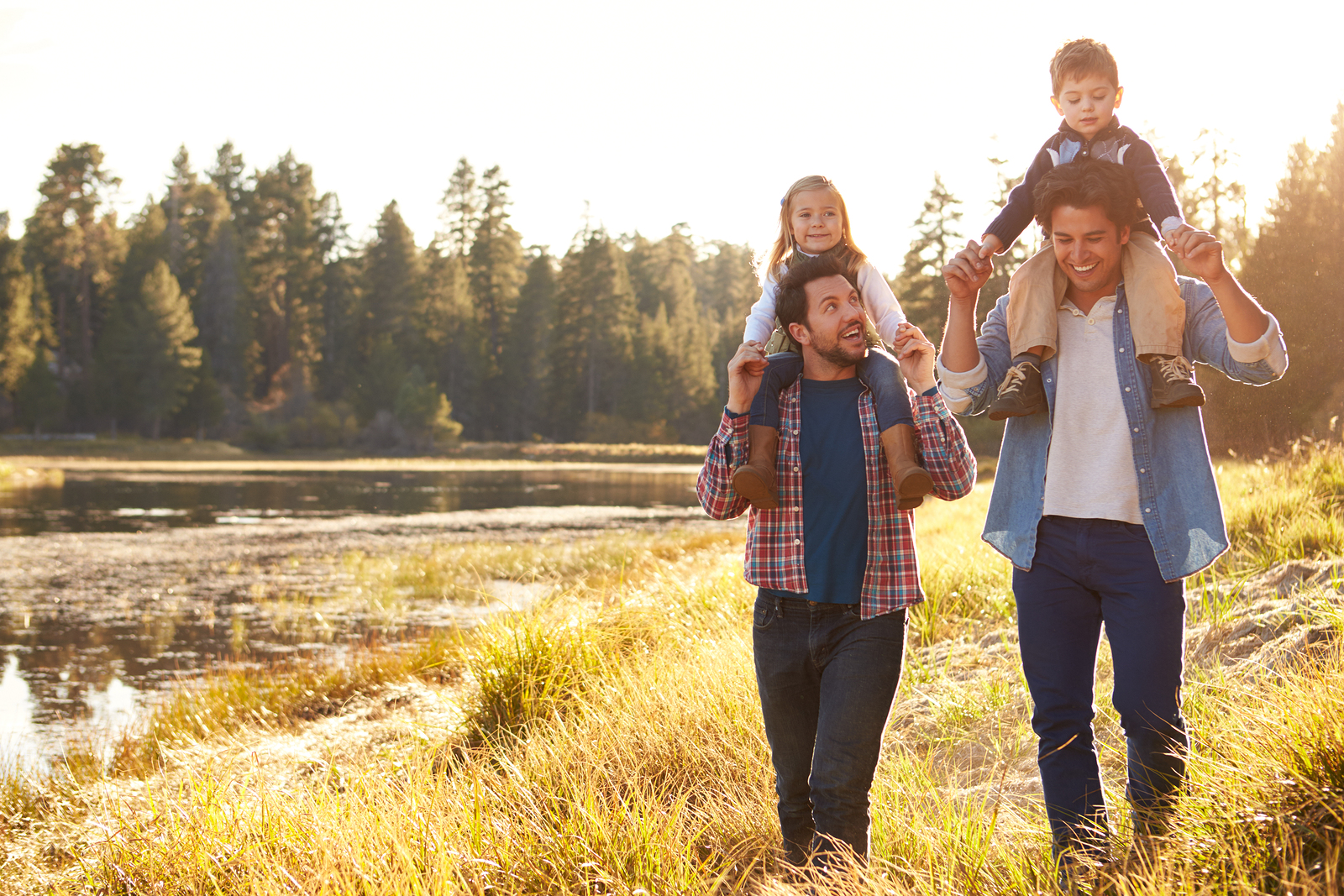 Male couple walking their children by a pond