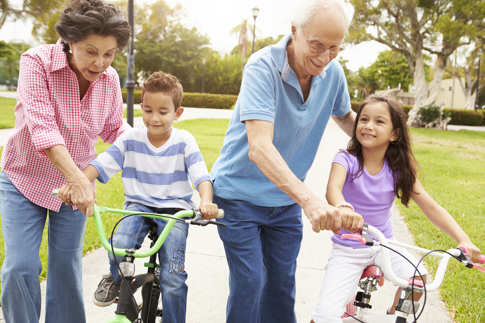 Grandparents teaching a boy and girl to ride their bikes