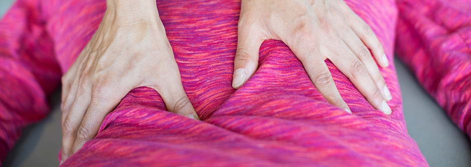A set of hands massaging a patient's back.
