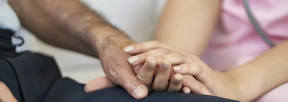 A nurse holding the hand of a cancer patient