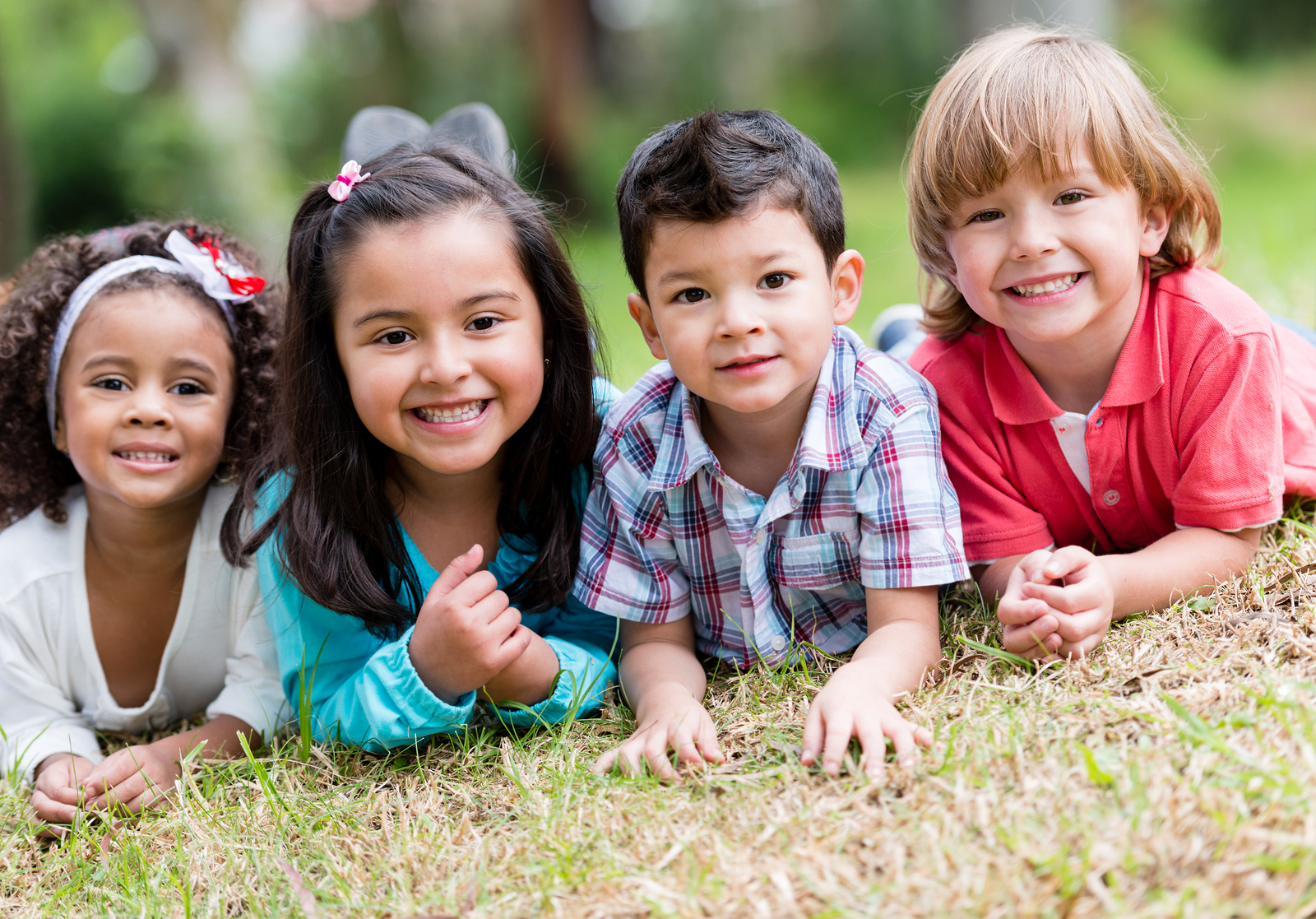 four young children lying on the grass