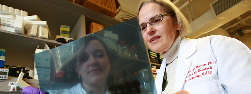 A researcher reviewing a slide with a student.