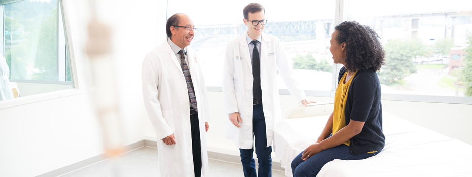 Dr. Charles Lopez and physician assistant Jeff Donovan warmly greet a patient in a brightly lit room at the South Waterfront campus