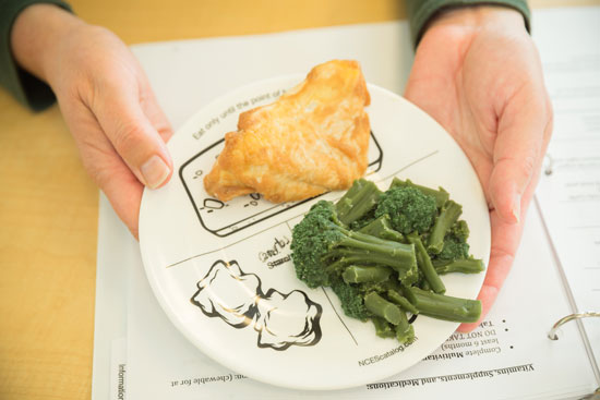 A meat and vegetable portion served on a plate that has markings on it to help guide serving sizes