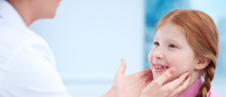 A doctor inspects a child's throat for thyroid issues.