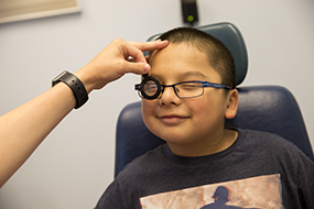 Happy boy with glasses having his eyes examined for glaucoma.