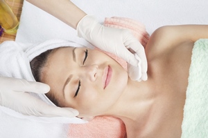A relaxed woman getting a waxing treatment done on her chin