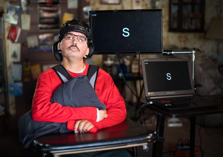 Gregory Bieker with brain-computer interface equipment, helmet and monitors