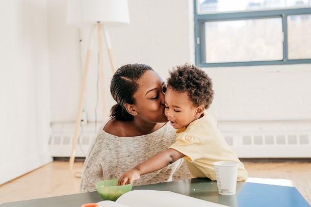 Mother kisses son as he reaches for a snack