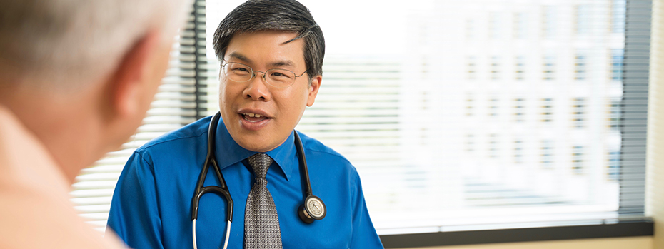 A doctor speaking with one of his patients in front of a window at 博彩网站.