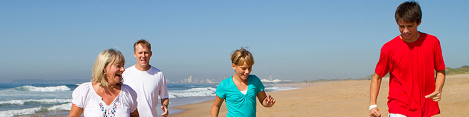 A family smiling while walking along the beach.