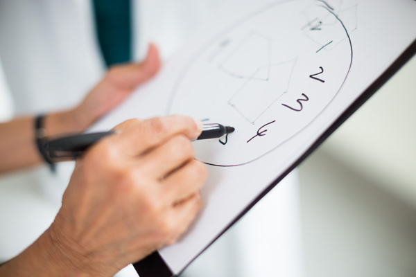 Hand drawing a clock face on a piece of paper on a clipboard