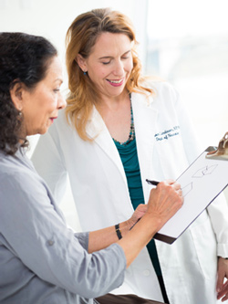 Allison Lindauer with a patient. Patient is drawing on a clipboard that Lindauer is holding.