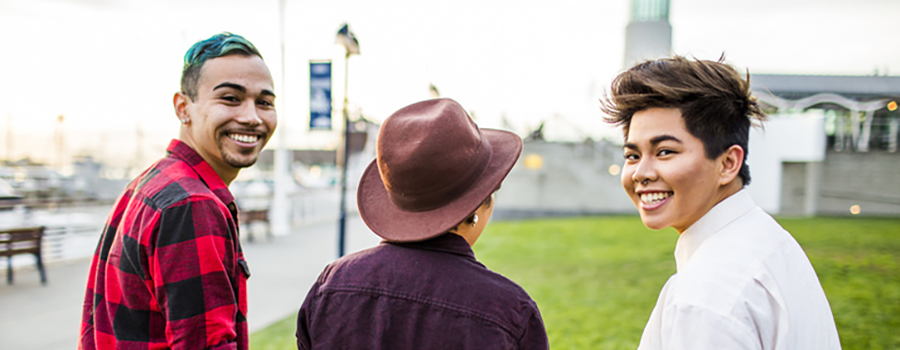 Three people walking away from the camera, two of them looking back and smiling