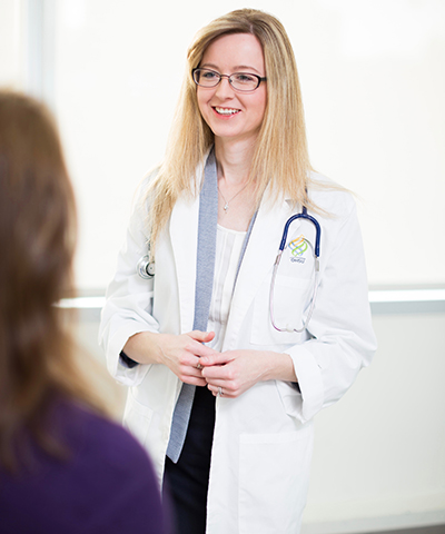 Dr. Elena Varlamov in a lab coat talking to a patient