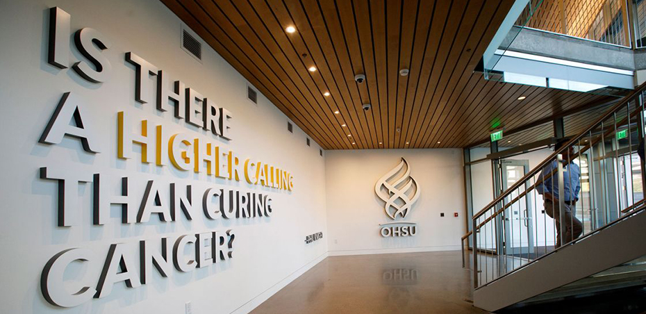 An interior shot of inside the 博彩网站 Knight Cancer Research Building, showing a wall that has the 博彩网站 logo on it, with the words "Is there a higher calling than curing cancer?" next to it.