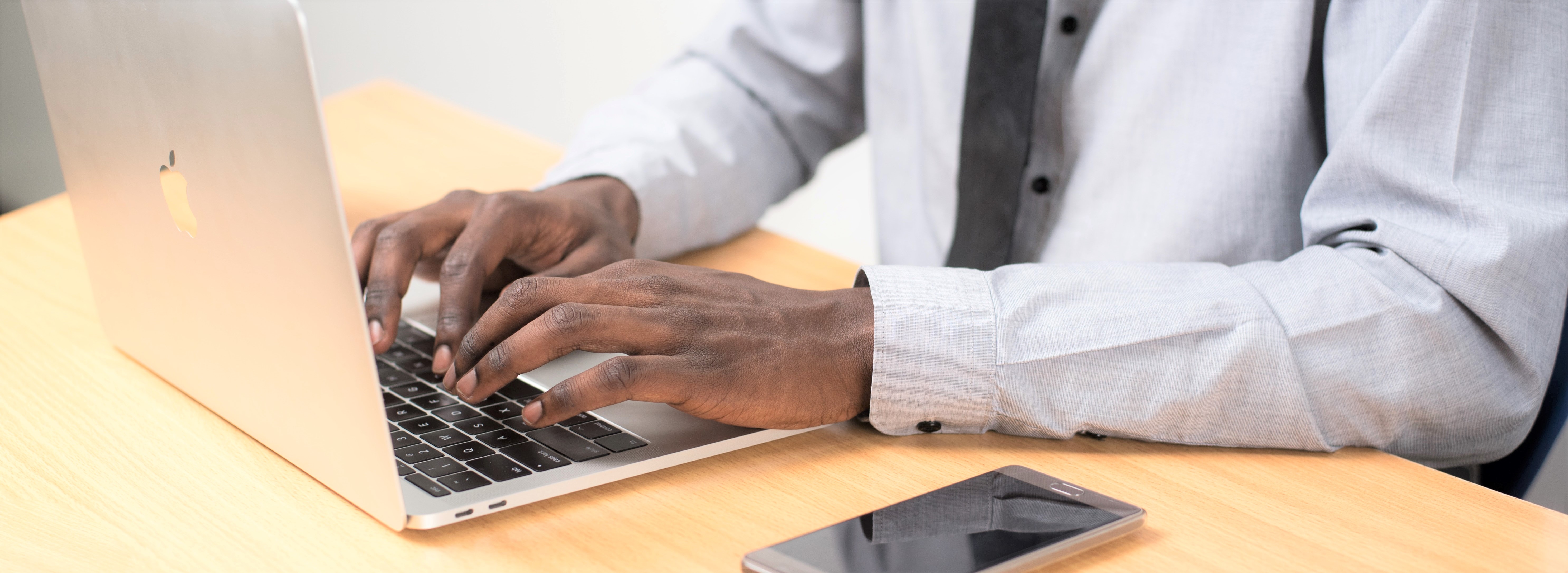 Person types on laptop wearing a button down and tie 