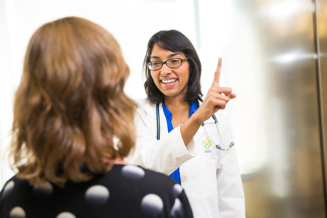 Dr. Hetal Choxi pointing her finger and having a female patient follow the finger with her eyes as part of an exam.