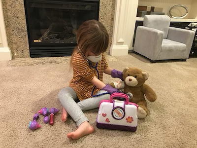 Sienna Balumas playing with her doctor kit on the floor in the living room.