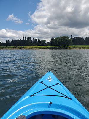 A POV photo inside a kayak looking out on a lake.