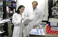 Two doctors, one male and one female, looking over a patient's chart in an office.