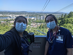 Two women in scrubs and wearing PPE face masks take a selfie at the top of the 博彩网站 tram.
