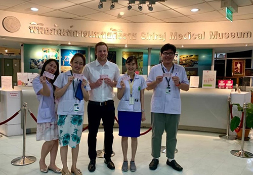 Five pediatric residents standing in a line holding up tickets at a museum.