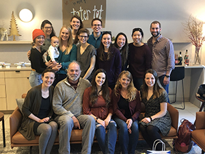 A group of people pose smiling while at a baby shower.