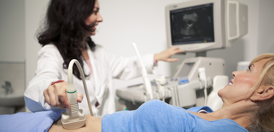 Ultrasound technician does an evaluation ultrasound on a woman in blue clothes.