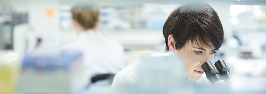 Scientist looks into microscope.