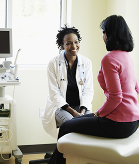 Doctor sits with patient in exam room