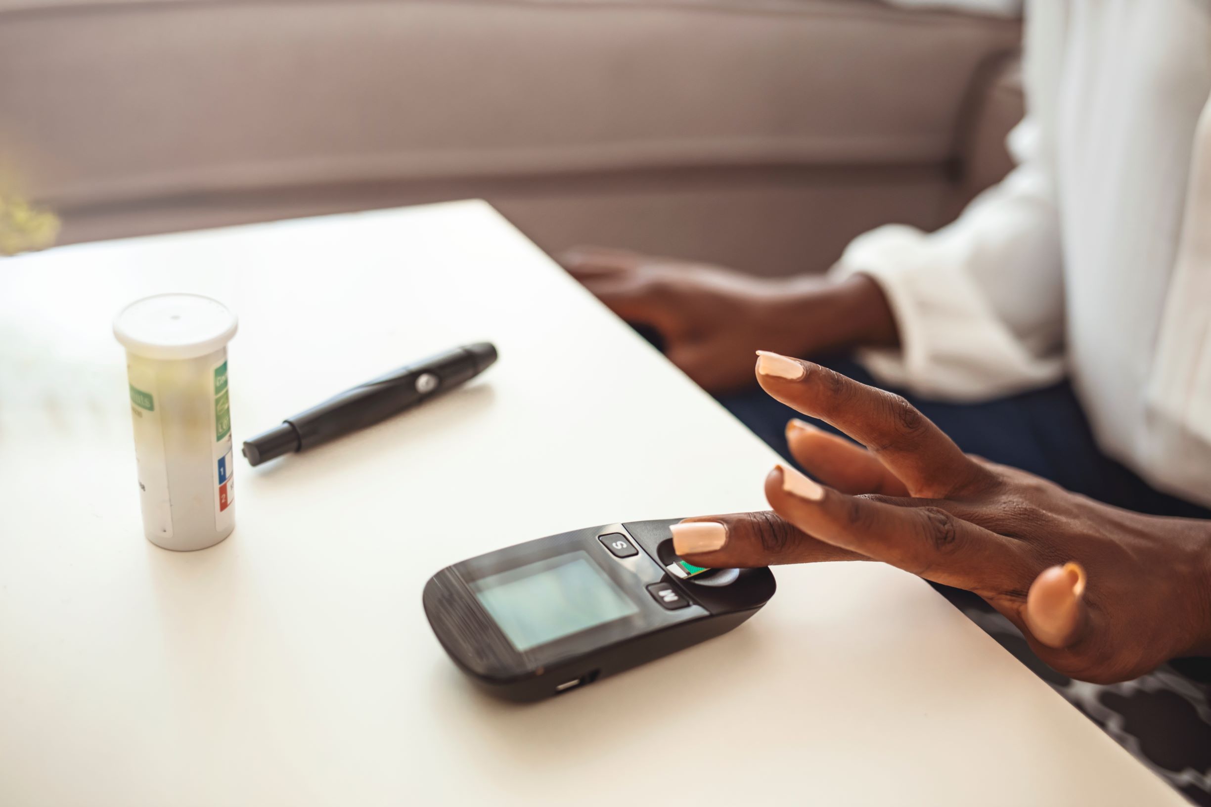 Woman's hand up close with finger resting on blood sugar test strip.