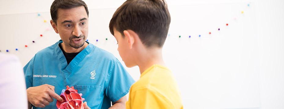 Pediatric heart surgeon Ashok Muralidaran showing a model heart to a child.