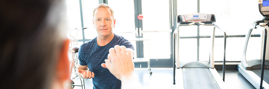 Photo of a person doing exercise while standing in front of treadmills