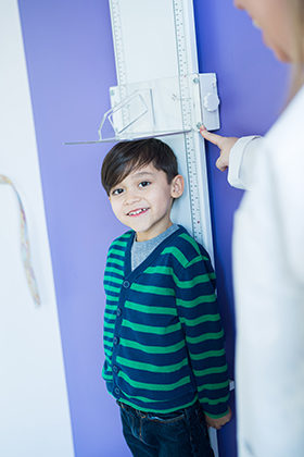 A little boy gets his height measured by a female doctor.