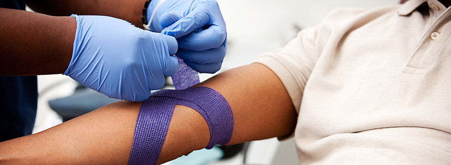 Photo of a person wearing gloves wrapping a bandage around another person's arm