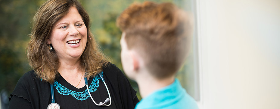 Photo of a female healthcare provider speaking with an adolescent patient.