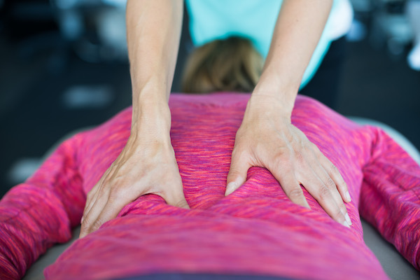 Photo of hands giving a back massage to a person wearing a pink sweater