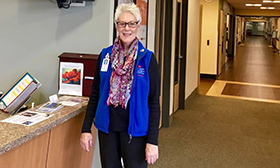 A woman standing near a hospital check-in counter smiling.