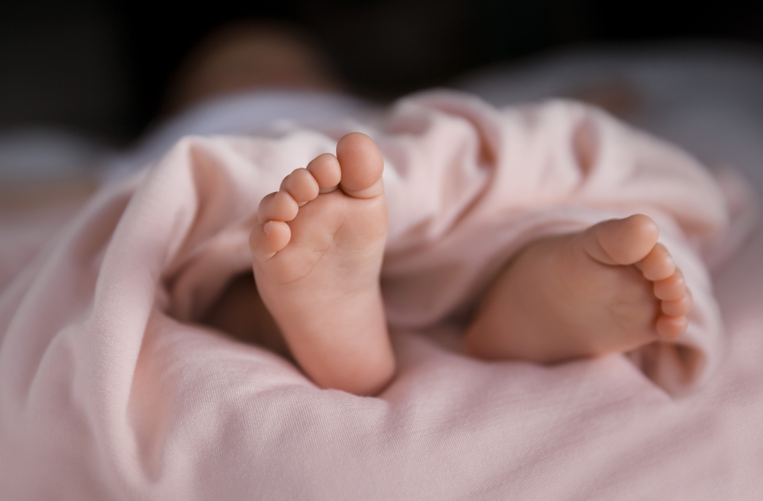 Baby's feet wrapped in peach colored blanket