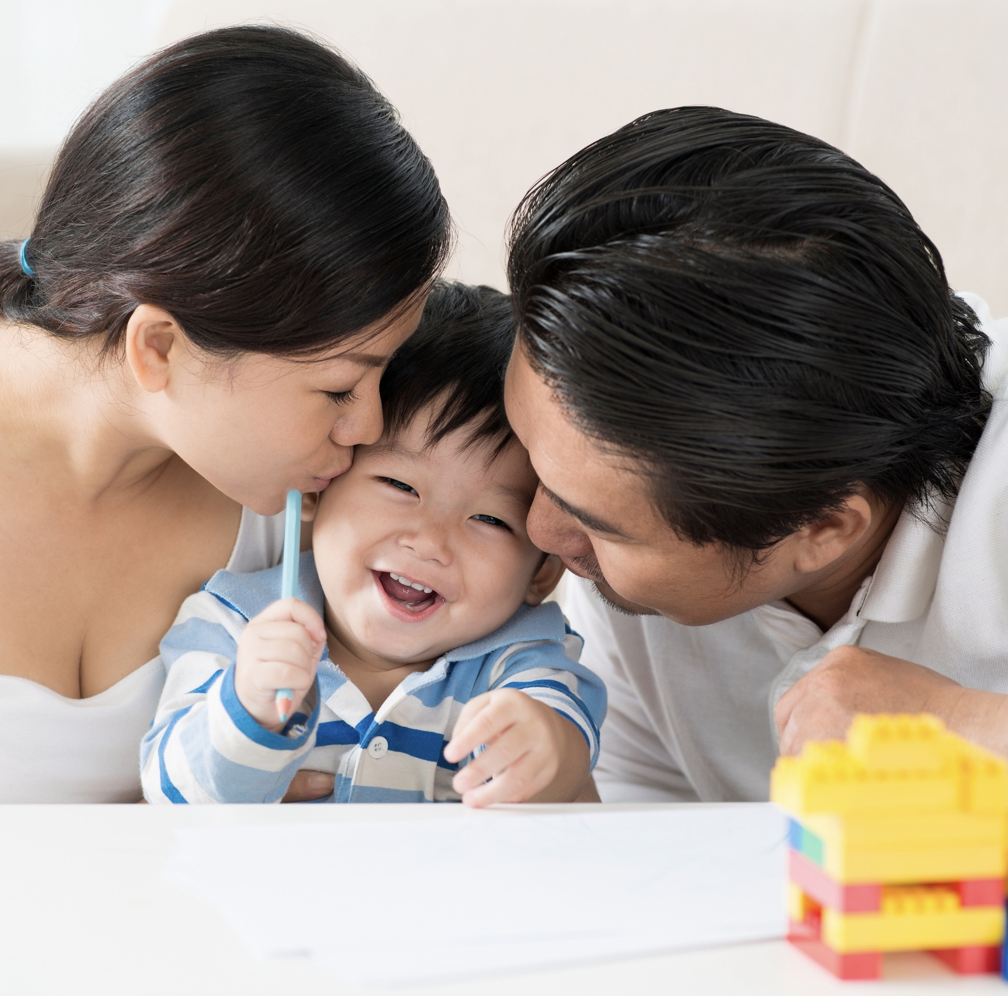 two parents kissing their child's cheeks